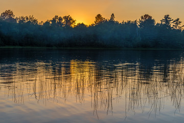 Sunset above forest lake