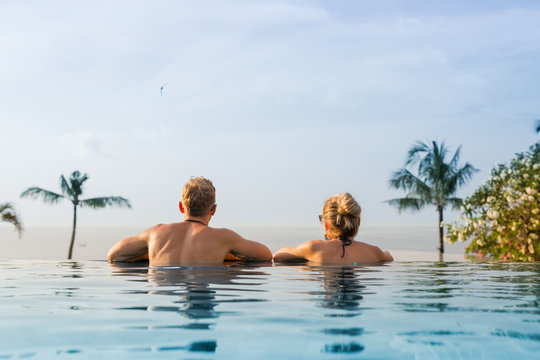 Couple in infinity pool looking at horizon