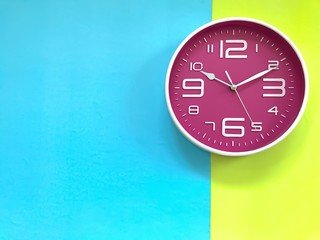 Closeup A deep pink wall clock set on pastel blue and green background. Theme of Working business time .The concept of " The time is going on." Top view with Selective focus. Copy space.