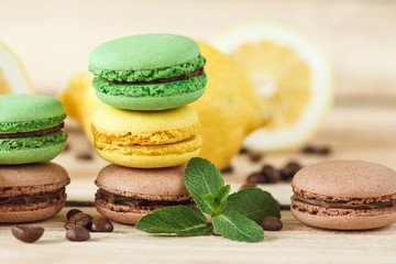 Green, yellow and brown french macarons with kiwi coffee beans and mint decorations