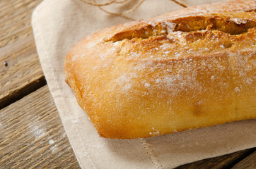 Ciabatta bread on a wooden table on baking paper. Rustic style, italian. Background
