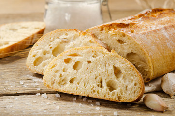 Ciabatta bread. Slices of ciabatta with garlic, salt on wooden table on linen cloth. Rustic style, italian. Close up