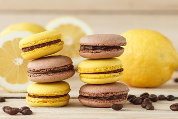 Yellow and brown french macarons with lemons and coffee beans on the wooden board