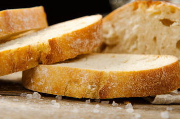 Ciabatta bread. Slices of ciabatta with garlic, salt on wooden table on linen cloth. Rustic style, italian. Close up