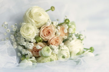 Beautiful bridal bouquet from pale pink roses and white ranunculus flowers on white linen fabric background. copy space