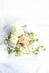 Beautiful bridal bouquet from pale pink roses and white ranunculus flowers on white linen fabric background. copy space