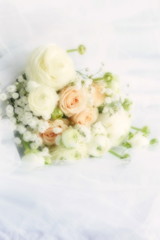 Blure effect, soft focus. Beautiful bridal bouquet from pale pink roses and white ranunculus flowers on white linen fabric background. copy space