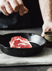 Man preparing beef steak on wooden table close up