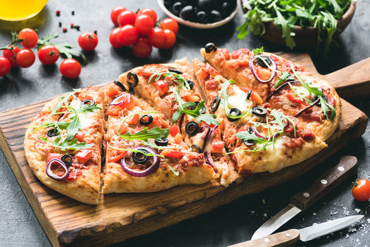 Homemade flatbread pizza garnished with fresh arugula. Selective focus