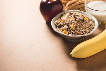 Oatmeal flakes in a bowl, milk, apple and banana on wooden table. Healthy breakfast concept. copy space