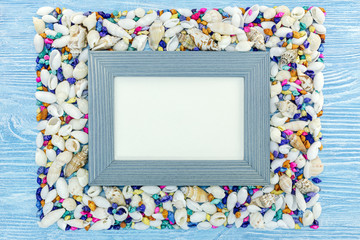 empty frame on wooden blue background with multicolor seashells. summer vacation concept 