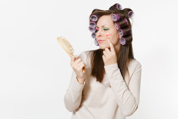 Young woman with curlers using combing with comb her hair isolated on white background. Crazy...