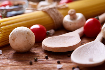 Uncooked pasta, tomatoes on wooden background, top view, close-up, selective focus