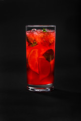 A single-colored, red cocktail in a glass with fine ice and lemon, lime and mint leaves from grapefruit. Side view. Isolated black background. Drink in a glass glass for the menu restaurant, bar, cafe