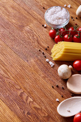 Uncooked pasta, tomatoes on wooden background, top view, close-up, selective focus