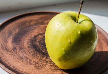 green apple on a plate in the sun