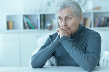 Fototapeta premium sad senior woman sitting at table