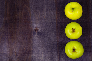 Three apples on a dark wooden background