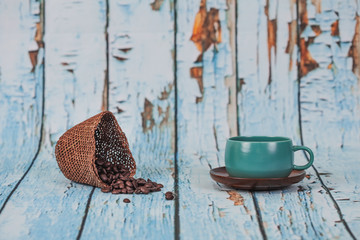 green coffee cup and coffee beans on old wood backgrounnd .