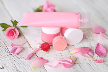 Obraz na płótnie Canvas cosmetics with rose extract. pink face cream, gel for washing with rose extract and rose petals on beige shabby chic background. Natural pure natural cosmetics
