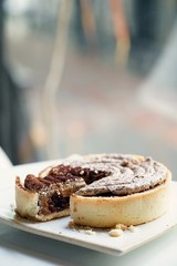 A tart was cut to a small piece and placed together, Delicious dessert with copy space, Italian dessert, rounded tiramisu tart placed on white plate. Tiramisu cake with Cinnamon and Coffee