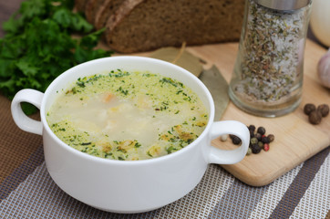 Mushroom soup with croutons in a white dish is on a wooden table.