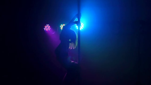 Silhouette of a sexy female pole dancing on black background. Slow motion. Smoke.