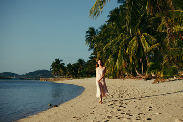 attractive woman walking in dress on ocean beach