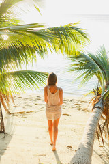 Rear view of woman standing between palm trees on seashore