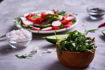 Still life of wooden plate with vegetables on white textured background, close-up, selective focus
