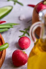 Fresh red radish in wooden bowl among plates with vegetables, herbs and spicies, top view, selective focus.