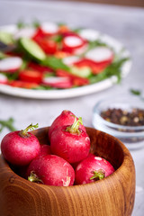 Naklejka na ściany i meble Fresh red radish in wooden bowl among plates with vegetables, herbs and spicies, top view, selective focus.