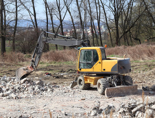 Fototapeta premium The excavator loads the load on the car. Construction works. Technology of urbanization. Heavy industrial machines. Building of the city. Mechanization of heavy manual labor. Modern technologies.