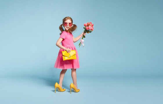 funny child girl fashionista in big mother's   shoes on colored background