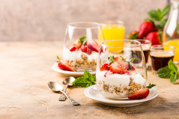Dessert with strawberries and yoghurt on light brown background. Copy space. Healthy breakfast food concept.