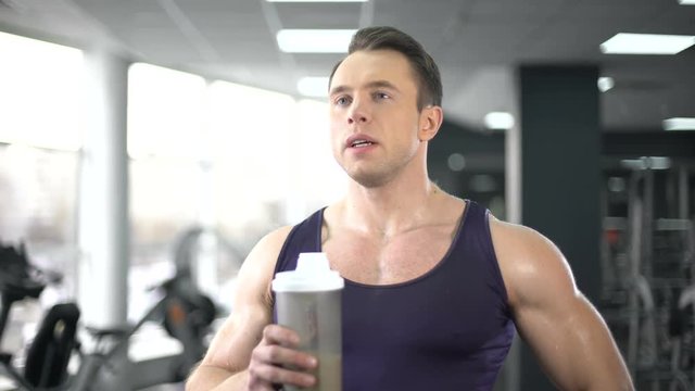Muscular man drinking protein shake after workout, healthy diet, bodybuilding