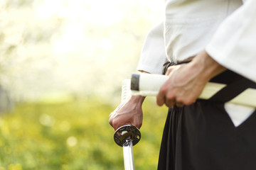 Young martial arts fighter with katana in the orchard.