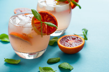 Blood orange cocktail with slices of orange on turquoise background