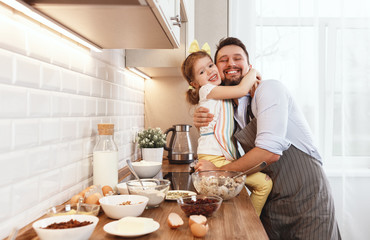 happy family in kitchen. Father and child daughter knead dough and bake biscuits