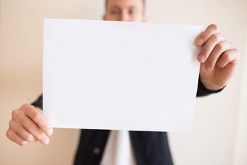 Man holding a blank white sheet of paper