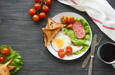 Fried egg, tomatoes, sausage, slices of bread and lettuce on a plate     