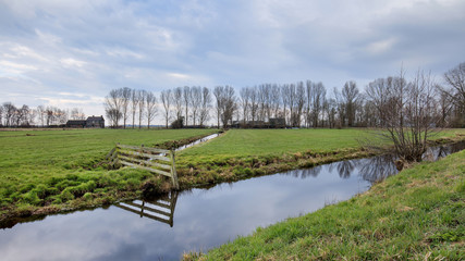 Dutch Landscape with a green meadow, ditch and cloudy sky, Netherlands