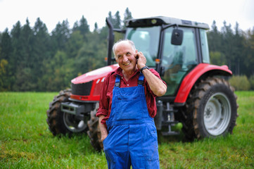 Proud farmer standing in front of his red tractor