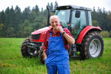 Proud farmer standing in front of his red tractor