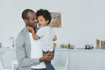 african american father hugging son at home