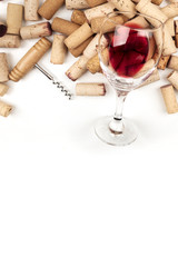 Glass of red wine with corks and corkscrew on a white background with copy space
