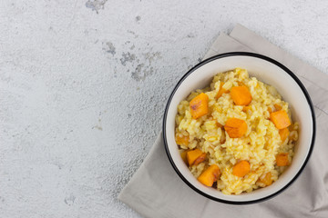 Risotto with pumpkin on a concrete background. Left for text. View from above.