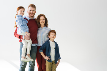 Fototapeta na wymiar happy redhead family with two children smiling at camera on grey