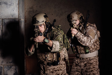 soldiers or private military contractors holding rifle. Image on a black background. war, army,...