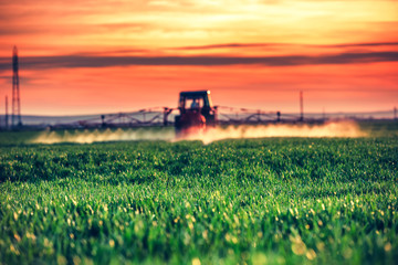 Farming tractor plowing and spraying on field © ValentinValkov